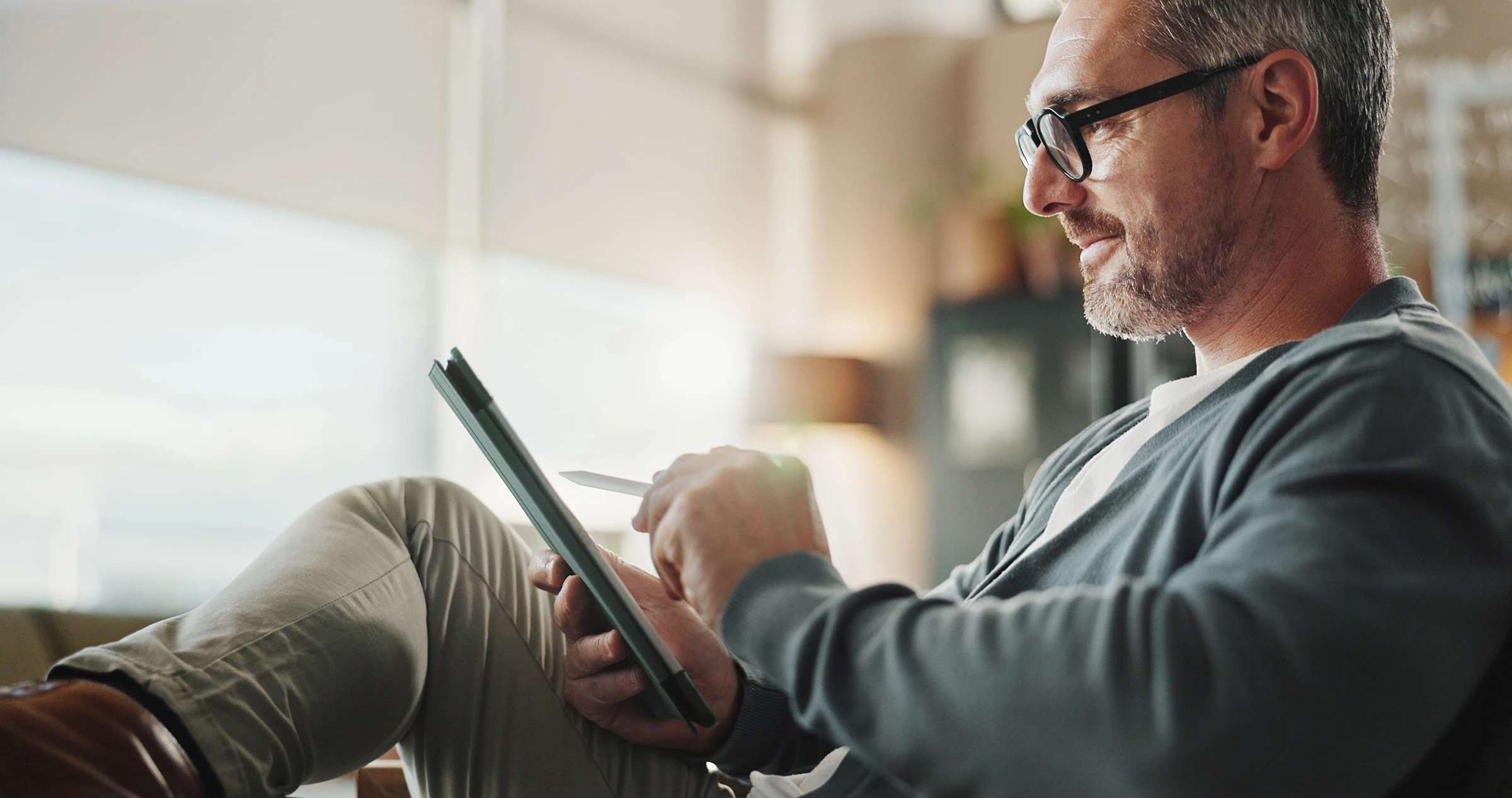 Man using a tablet with a stylus while relaxing at home or in an office setting